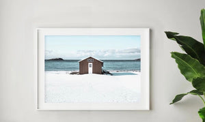 Brown boat shed on beach sand with blue ocean in backgroun